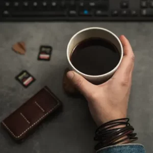 Gros plan sur un bureau avec des cartes mémoires et une main tenant une tasse de café pendant l'élaboration d'une stratégie SEO