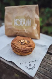 Photo d'un feuilleté coeur praliné noisette devant le sac de la boulangerie de Christophe Michalak