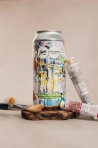 Mise en scène d'une canette de bière Fauve avec des tubes de peinture et pinceaux